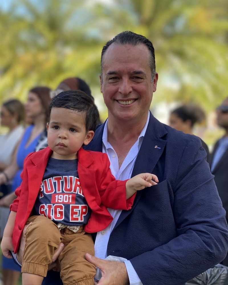Juan Molina holding a young boy in a Future SigEp shirt